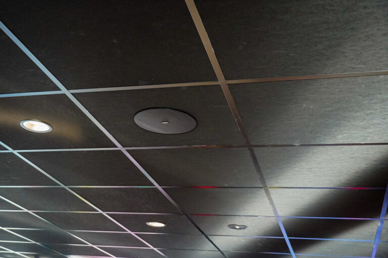 Zwart systeemplafond in de showroom van Verhoeven, met zwarte Biamp plafondluidspreker.