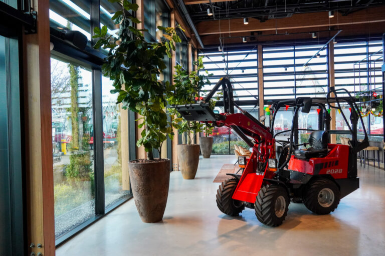 Rode model graafmachine in de showroom van Verhoeven, naast een grote kamerplant en links bovenaan in de afbeelding de Sonora 6TN speaker.